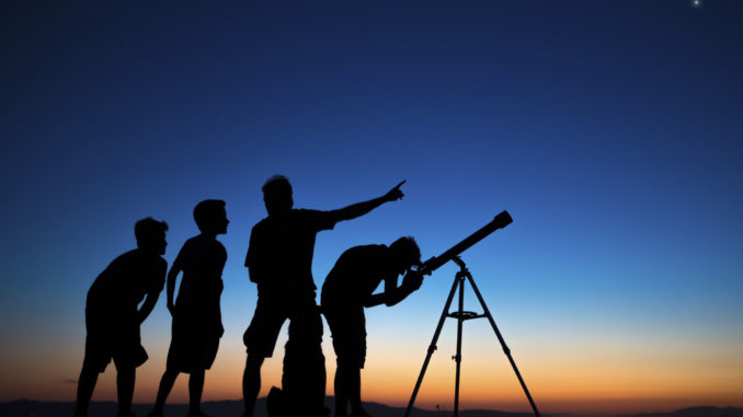 Dad and three sons on a clear night looking thru a telescope