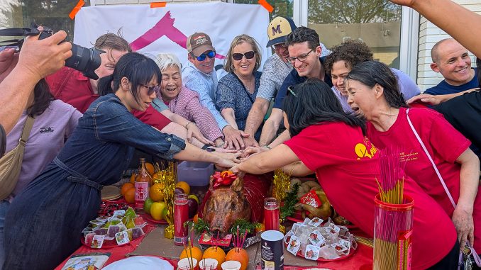 Members of the Greater Malden Asian American Community Coalition (GMAACC) and city staff prepare to make a ceremonial cut into a roast pig