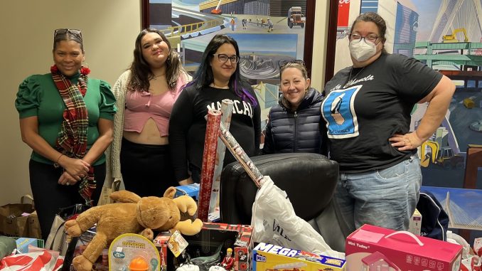 Volunteers in back of gift wrap and toys.